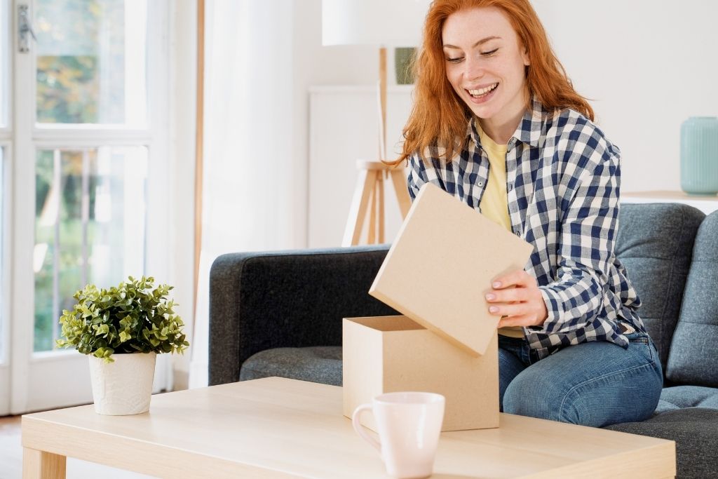 woman sitting on a couch opening a package